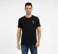 Man wearing black men’s t-shirt with minimal chest logo, short sleeves, regular fit on plain background
