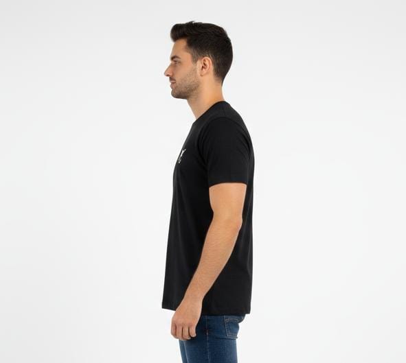 Side view of man wearing black men’s t-shirt with minimal chest logo, short sleeves, regular fit on plain background
