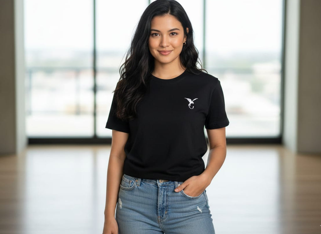 Woman wearing black women’s t-shirt with minimal chest logo, casual fit, front view in indoor lifestyle setting
