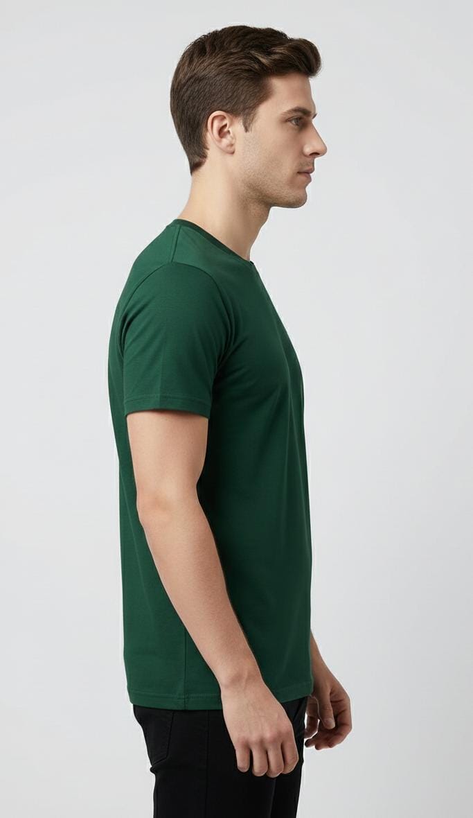Side view of man wearing dark green men’s t-shirt with minimal chest logo, short sleeves, regular fit on plain background
